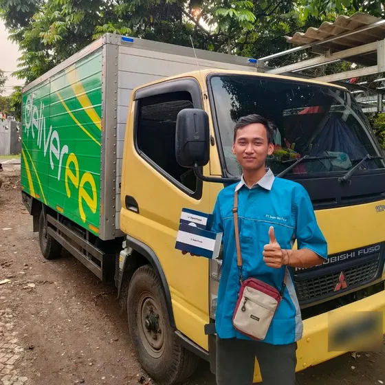 Teknisi gpssupertrack berseragam di depan truk pengiriman milik pelanggan armada